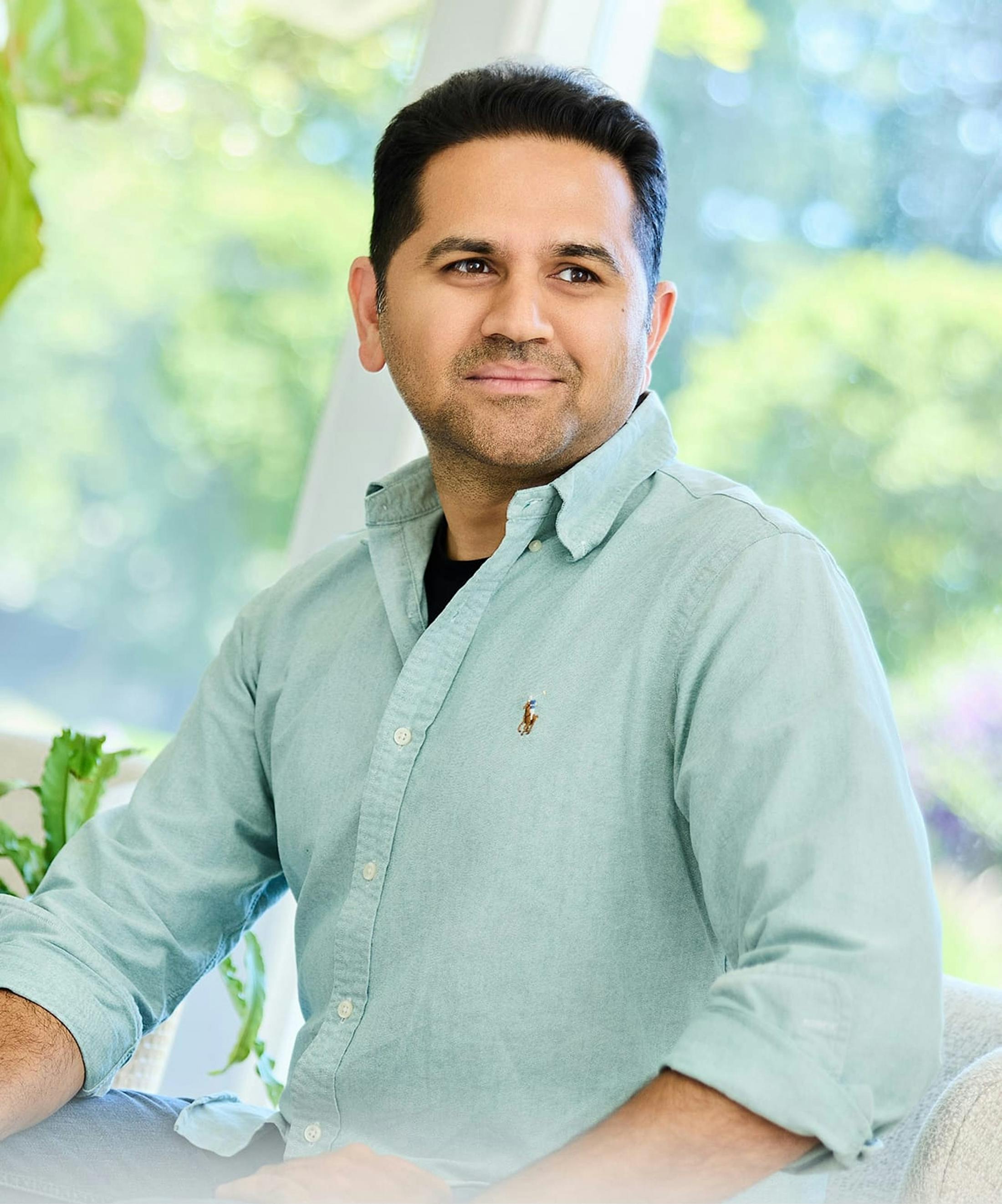 Man standing outdoors in a green setting, representing hair restoration
