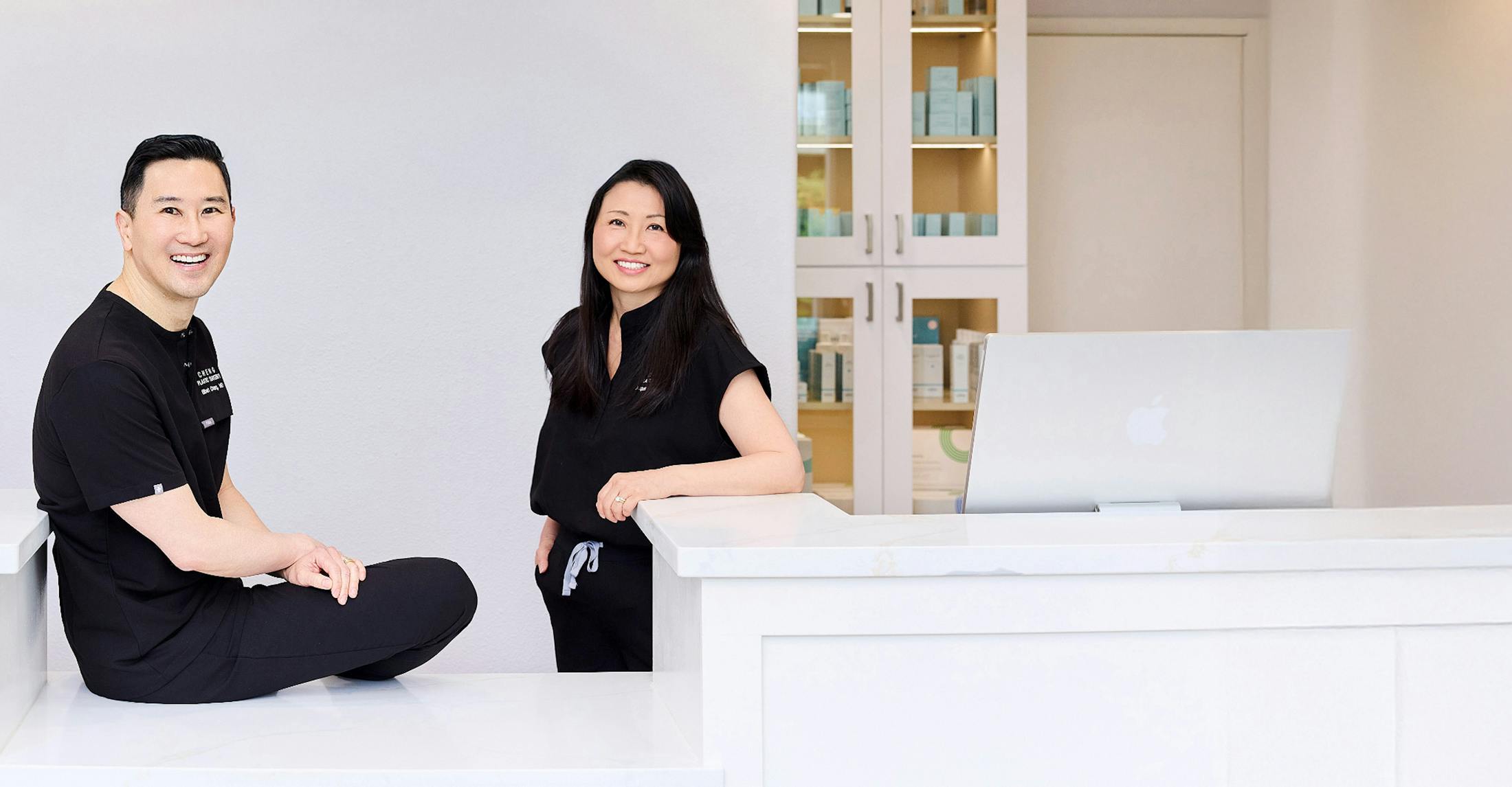 Dr. Elbert Cheng and Dr. Jacqueline Cheng smiling casually in a modern clinic room