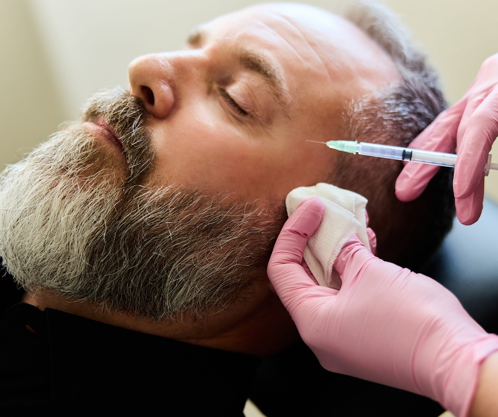 man receiving injections in face