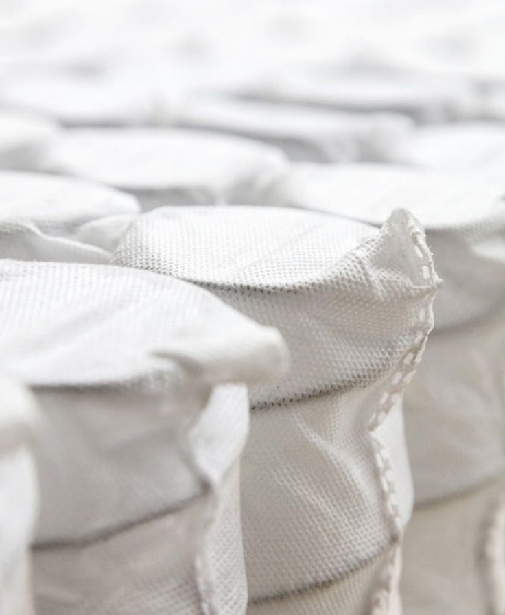 Dettaglio di molle insacchettate singolarmente in tessuto bianco, parte interna di un materasso.