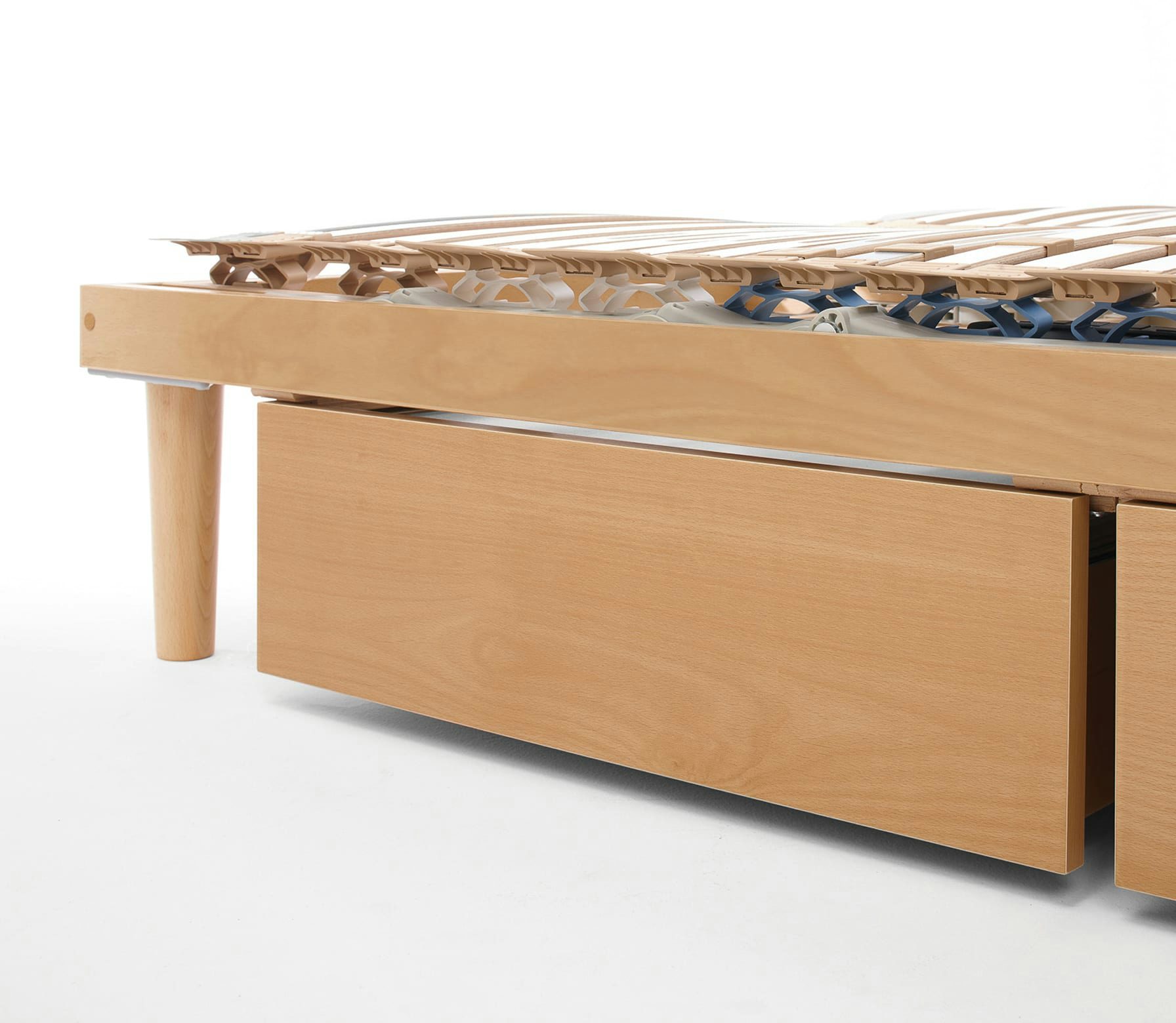 Struttura letto in legno chiaro con rete a doghe e cassetto contenitore estraibile nella parte inferiore.