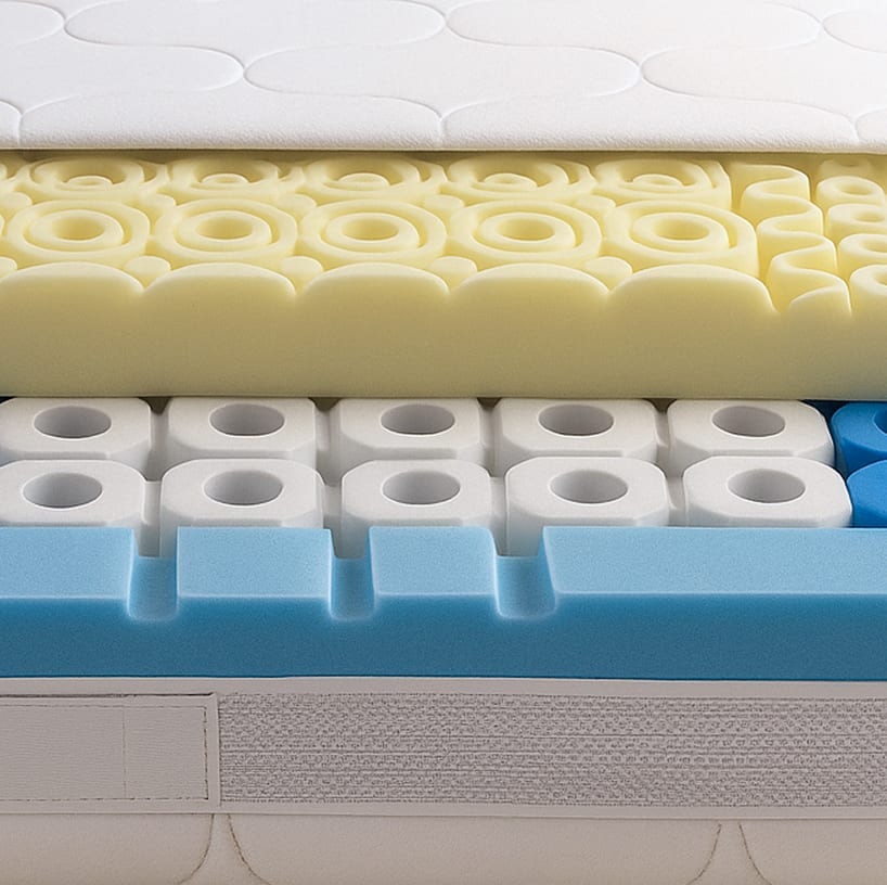 Struttura interna di un materasso a strati con schiuma gialla sagomata, cubetti bianchi con fori e spessore blu in schiuma.