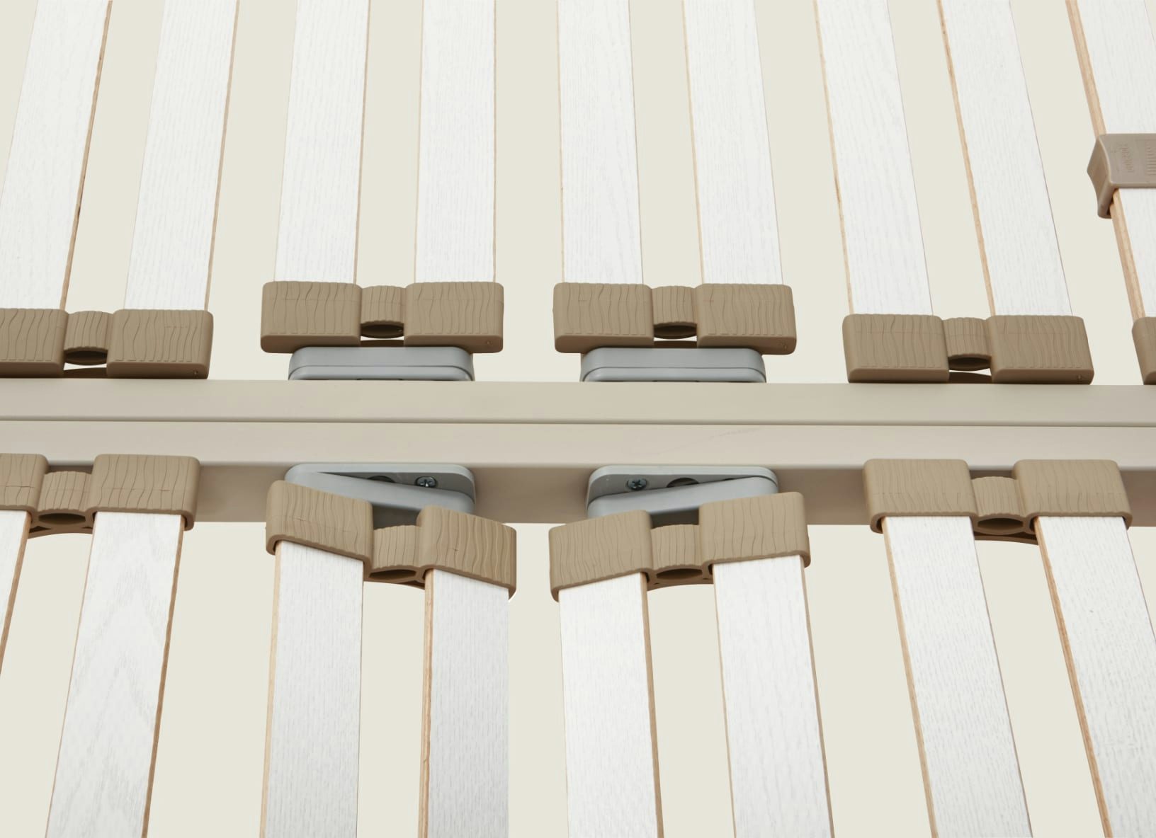 Dettaglio di doghe in legno flessibile con supporti in plastica beige montati su struttura metallica beige.