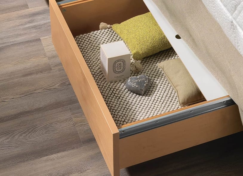 Cassetto in legno sotto il letto con tappetino grigio, due cuscini verdi e beige, confezione con logo ORANGER e cuore…