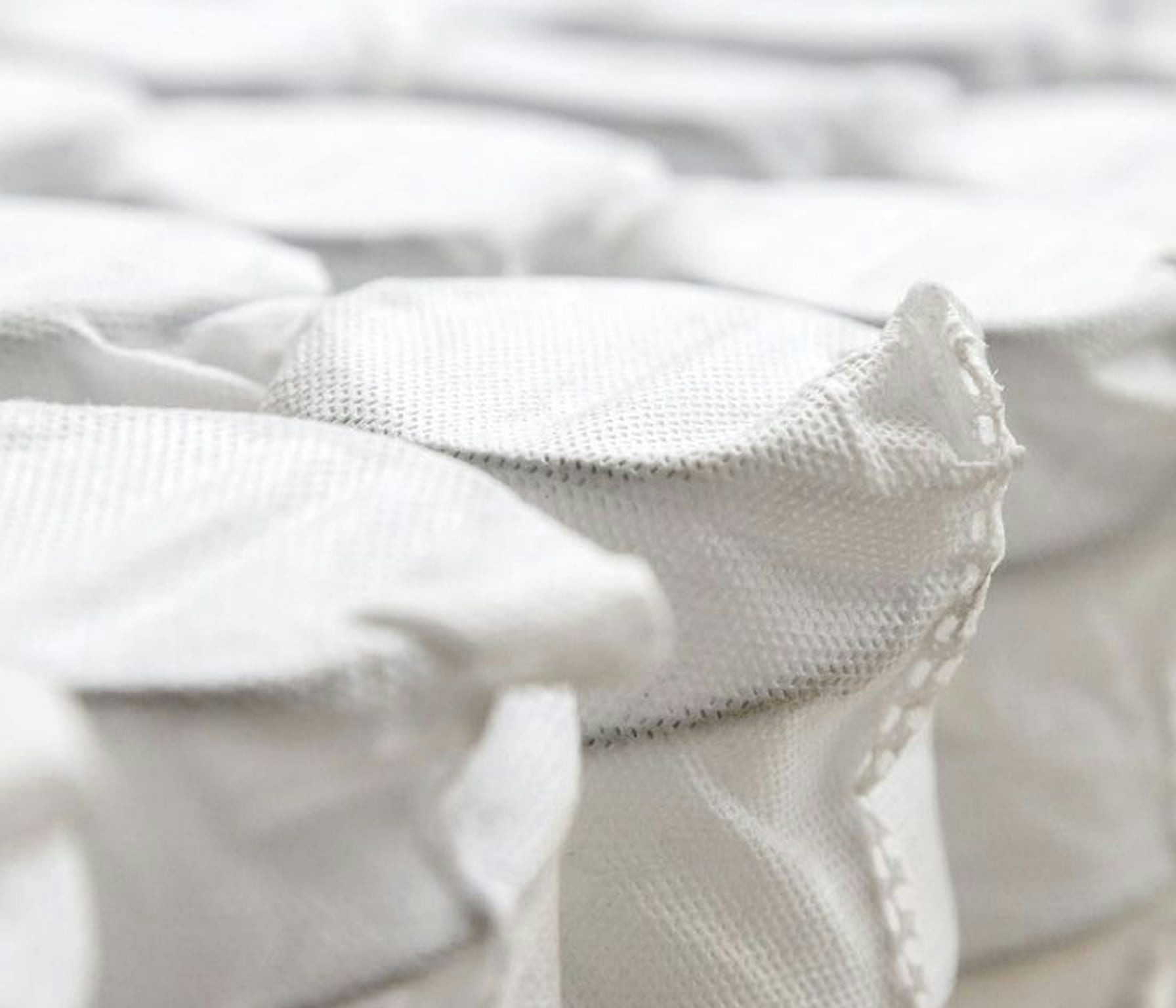 Dettaglio ravvicinato di molle avvolte in tessuto bianco, partizione di materasso a molle indipendenti.