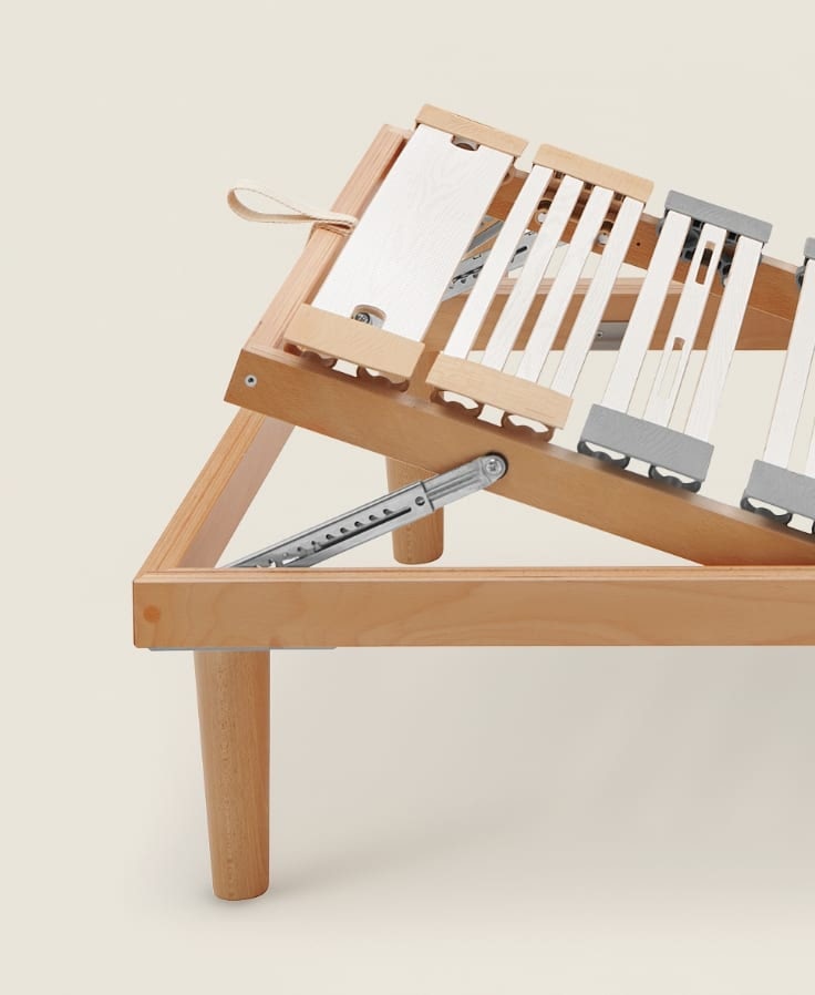 Struttura letto in legno chiaro con doghe regolabili in legno chiaro e grigio, parte superiore sollevata.