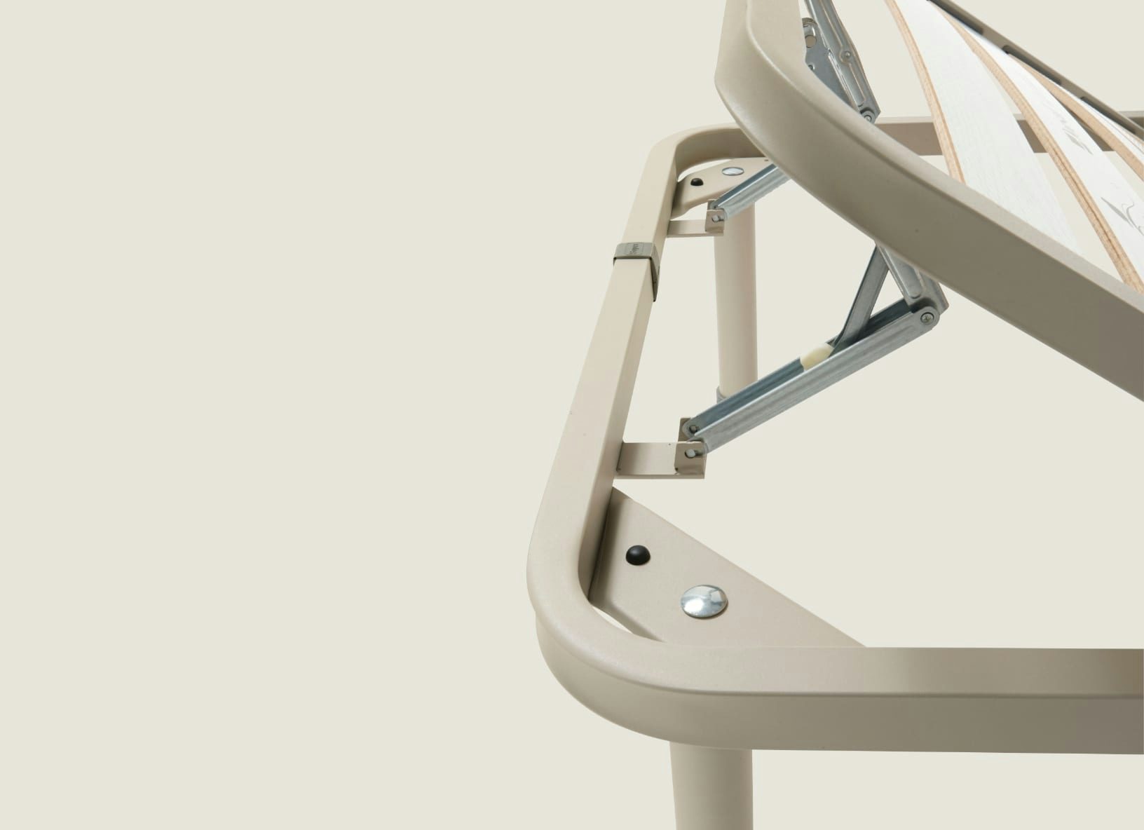 Meccanismo metallico di regolazione fissato a telaio beige con piedi cilindrici, parte di base reclinabile in legno chiaro.