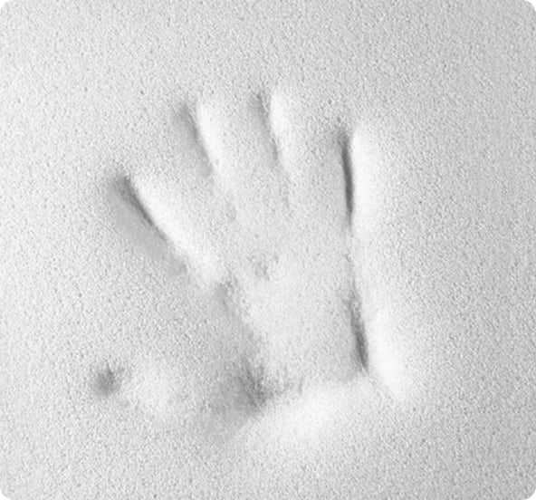 Impronta di mano sinistra impressa in una superficie bianca polverosa o farinosa.