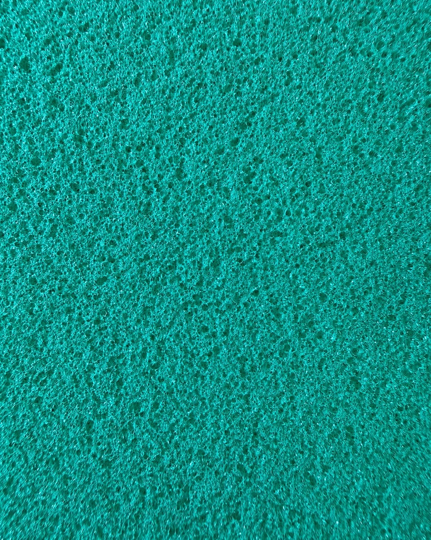Superficie verde acqua a pori irregolari e dalla struttura spugnosa, con micro fori distribuiti uniformemente.