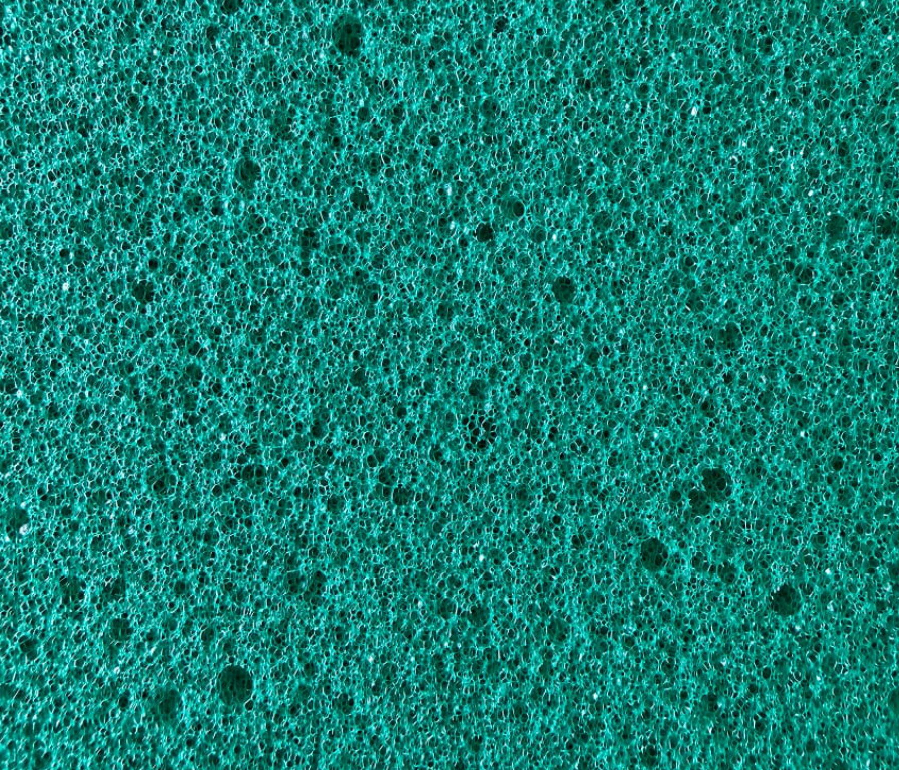 Superficie verde smeraldo con texture spugnosa e pori irregolari di varie dimensioni distribuiti uniformemente.