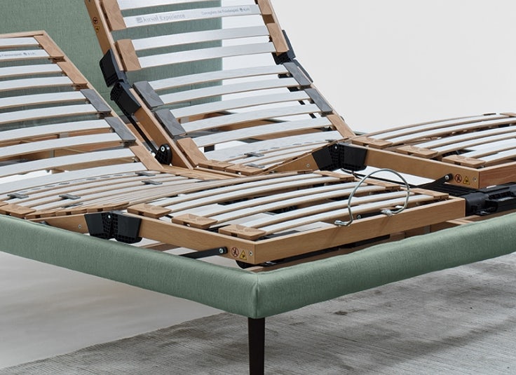 Struttura letto matrimoniale con rete reclinabile a doghe in legno su base imbottita verde e piedini in metallo nero.