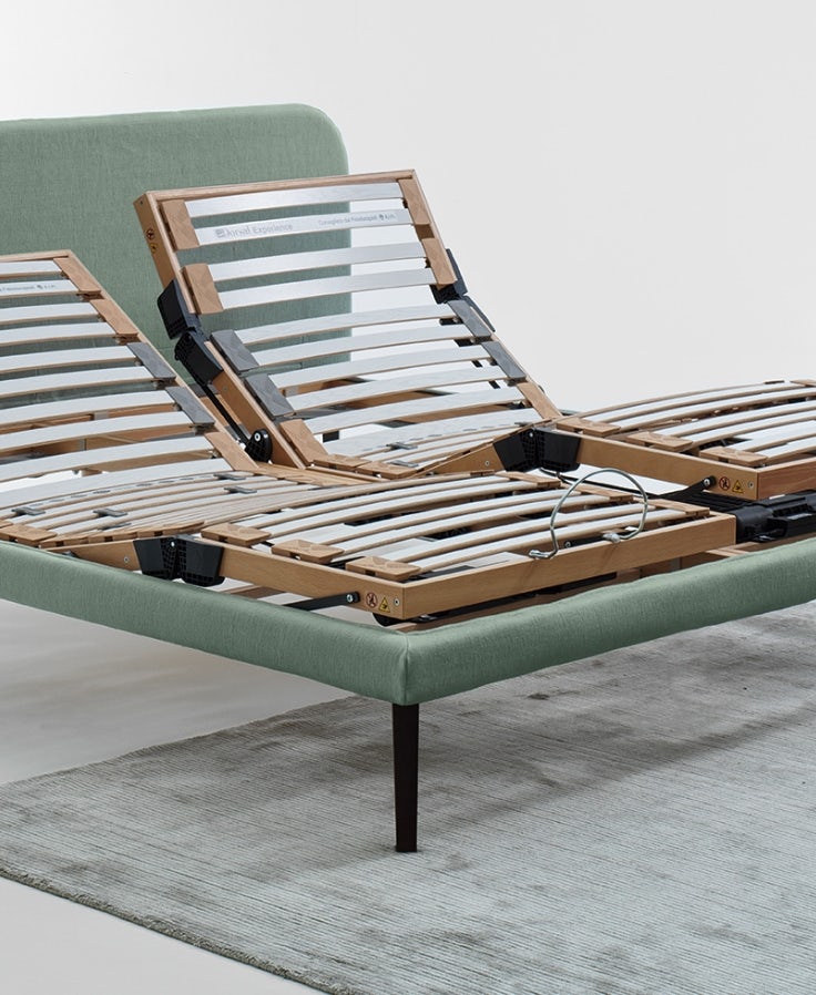 Struttura letto matrimoniale con rete reclinabile a doghe in legno su base imbottita verde e piedini in metallo nero.