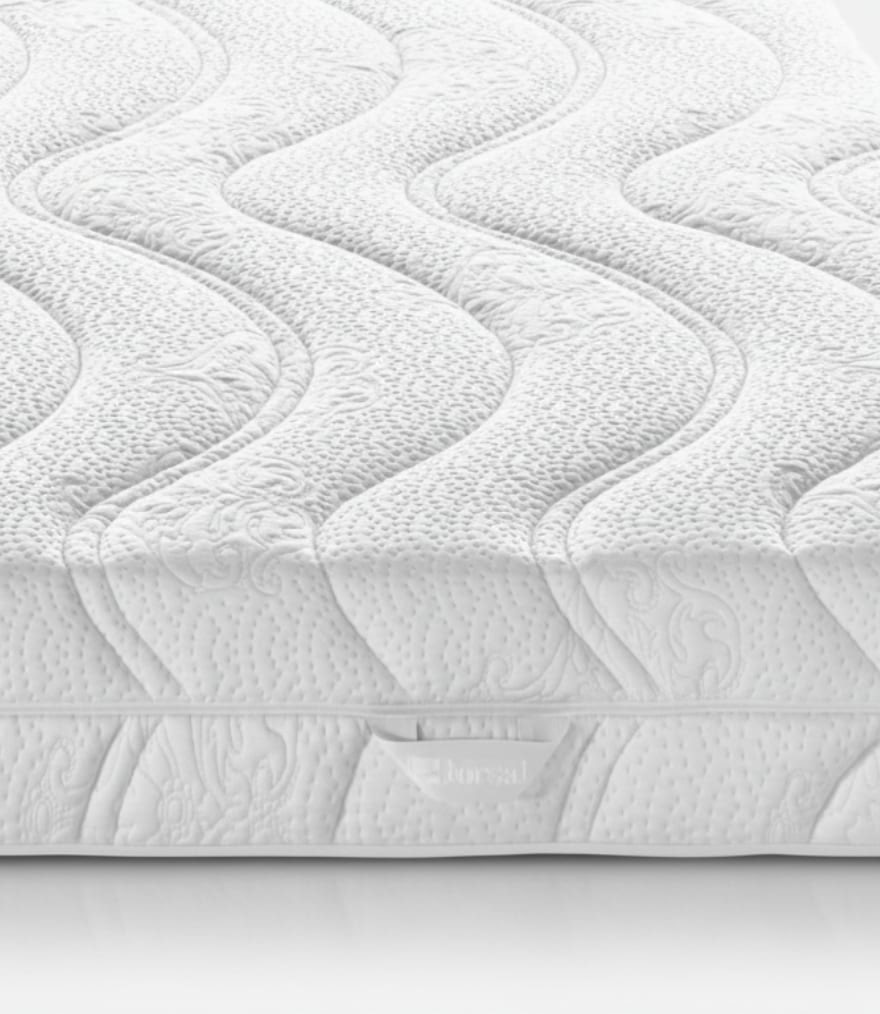 Superficie materasso bianca con motivo a onde e dettagli trapuntati che creano un effetto texture.