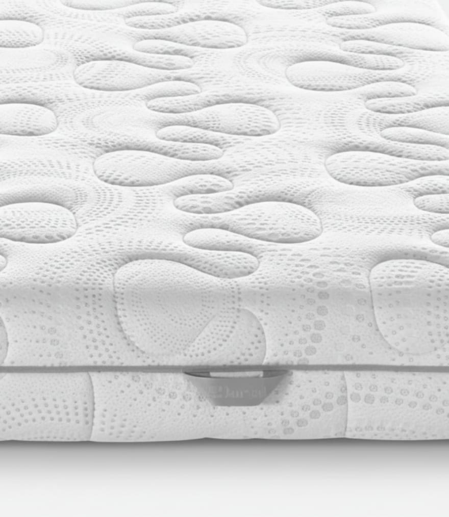 Superficie materasso bianca con motivo a rilievo di forme organiche e micro-perforazioni circolari.