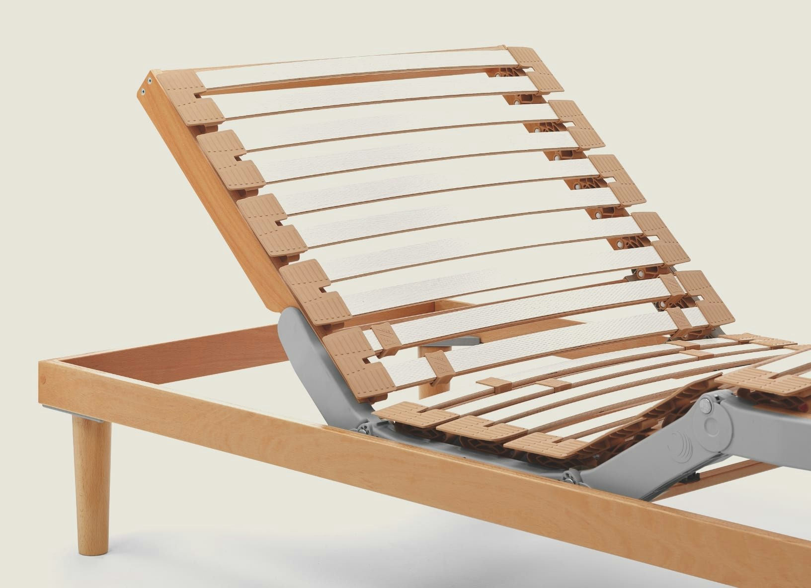 Rete letto regolabile con doghe in legno chiaro e struttura in metallo grigio, piedi in legno cilindrici.