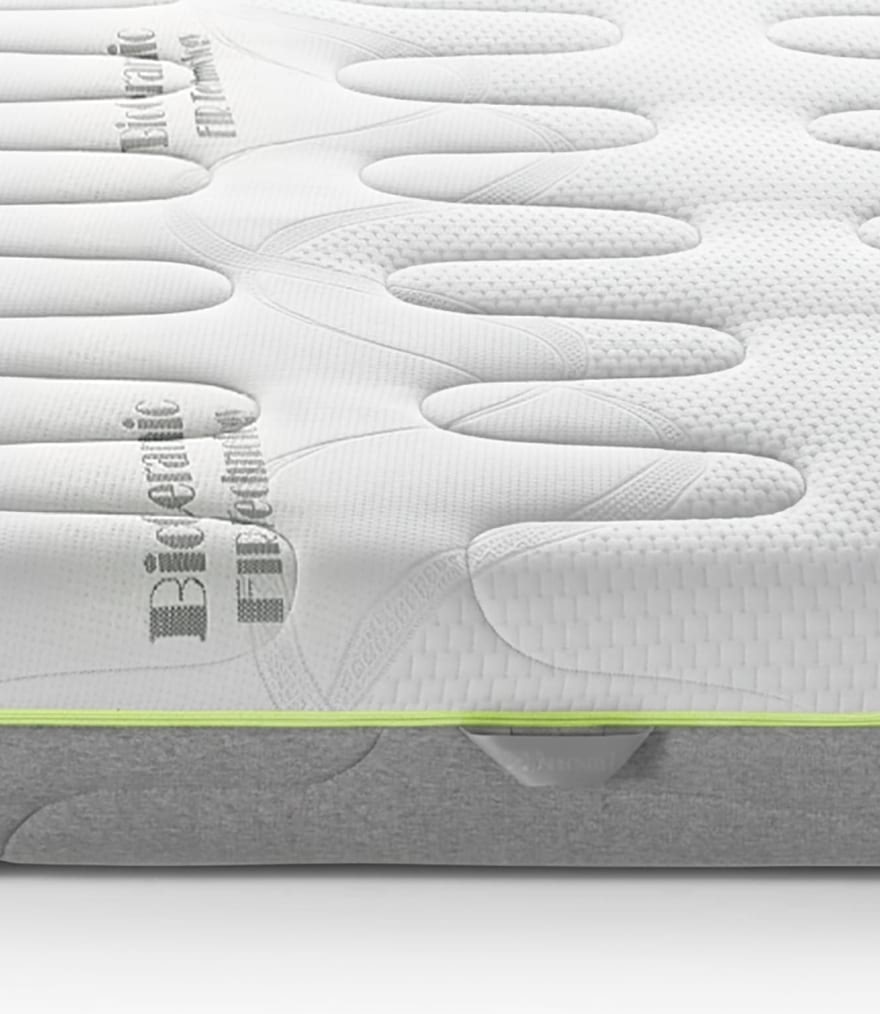 Materasso con superficie in tessuto bianco trapuntato con motivo a forma di mani e bordo grigio con striscia verde.