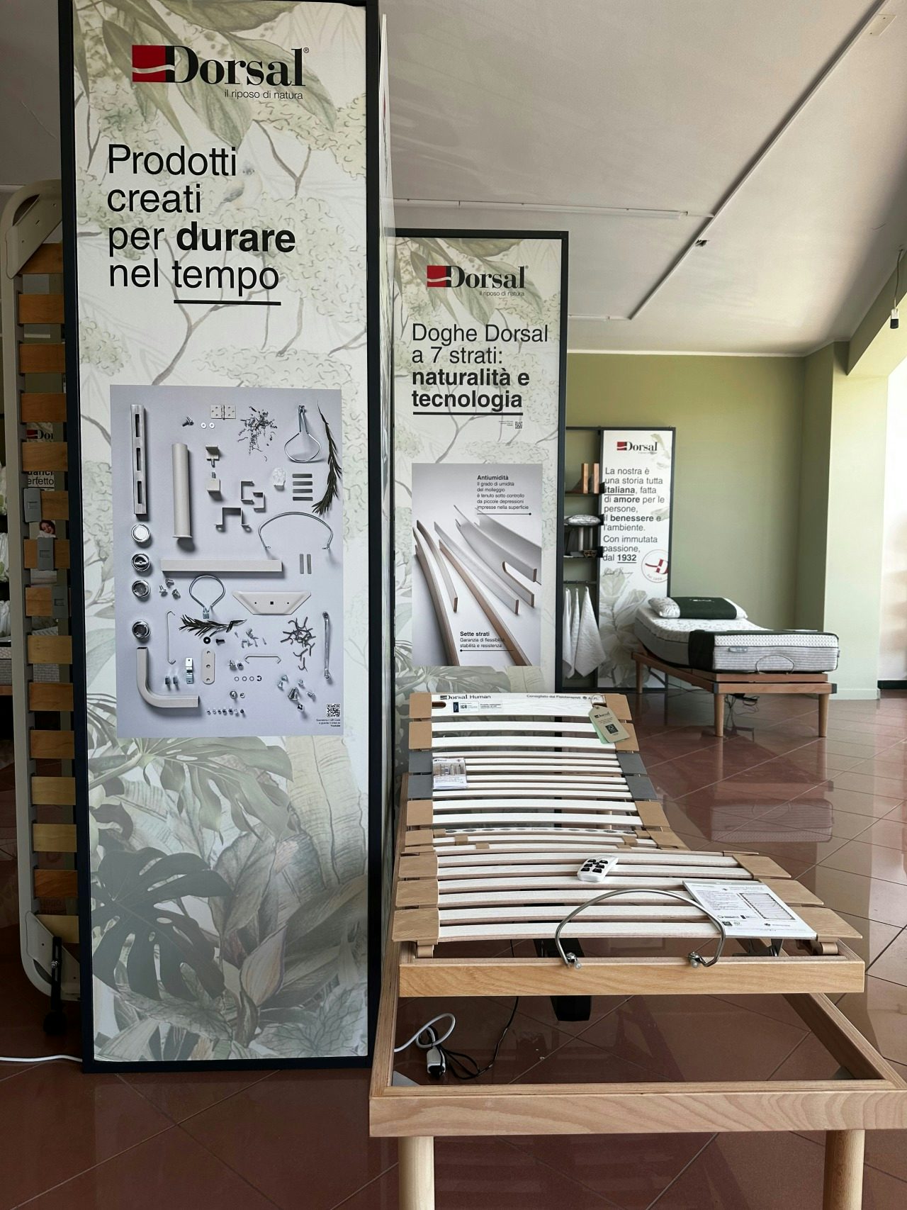 Letto ergonomico regolabile Dorsal in legno con spalliera a doghe davanti a pannelli informativi aziendali nel negozio…