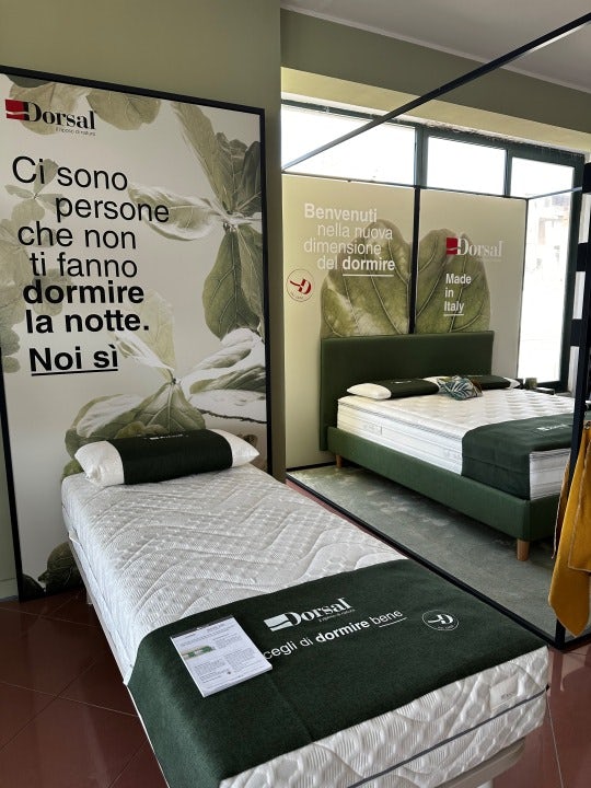 Letto singolo con coperta verde e cuscino bianco con verde in stanza con poster motivazionale Dorsal sul sonno.