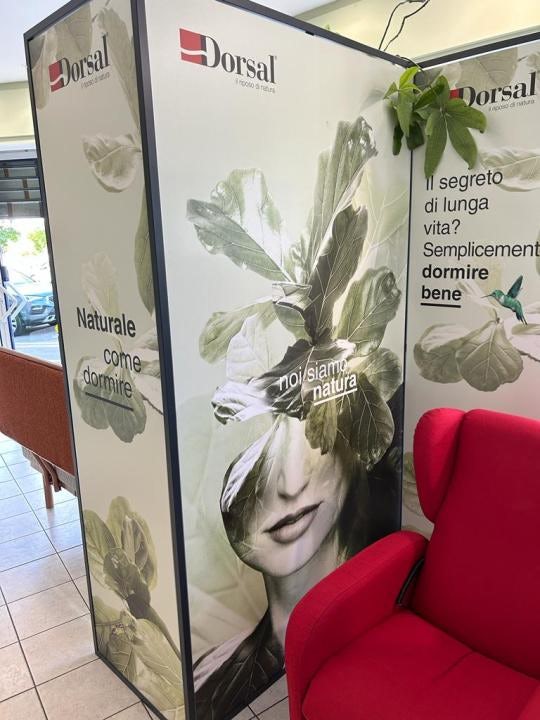 Pannello pubblicitario Dorsal con volto femminile sovrapposto a foglie verdi e messaggi sul dormire bene, poltrona rossa in…