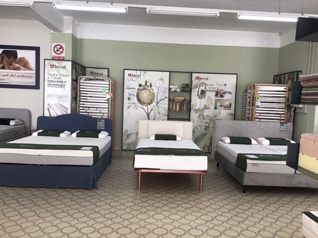 Tre letti matrimoniali in esposizione con biancheria verde in negozio di arredamento per la camera da letto.