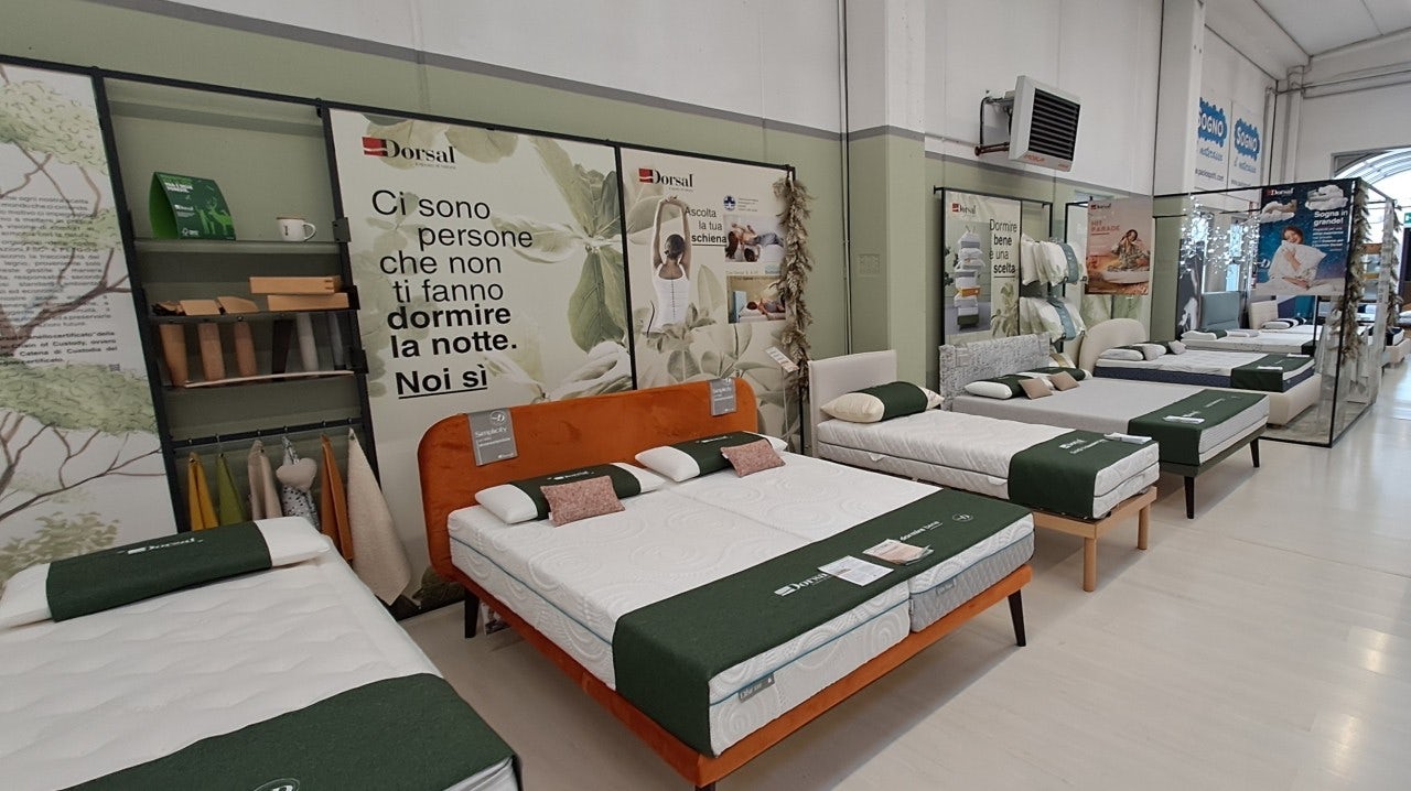 Negozio con diversi letti esposti con materassi Dorsal e poster promozionali alle pareti.