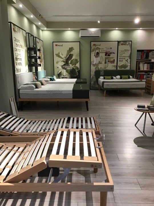 Letti con strutture regolabili in legno e materassi su pavimento in laminato, pareti verdi con poster pubblicitari.