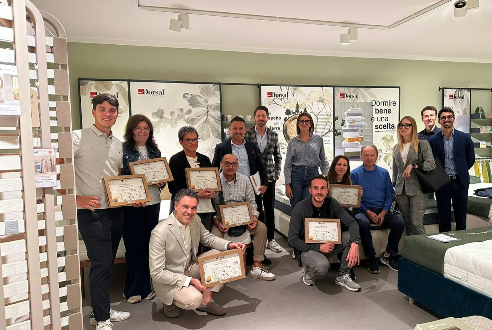 Gruppo di persone in negozio di letti e materassi con sei persone che tengono un certificato premi Dorsal sul sonno.