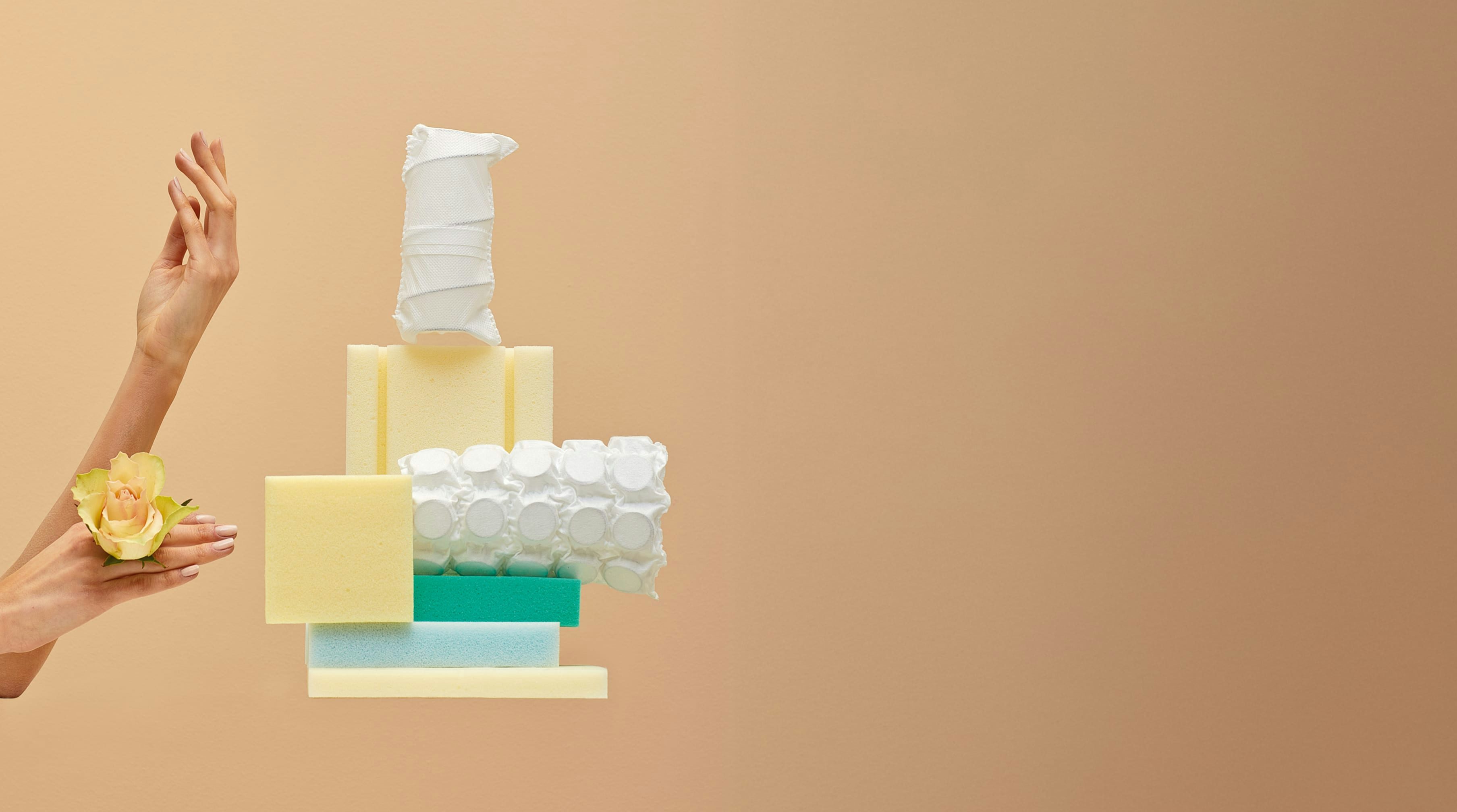 Mani con rosa gialla accanto a diverse tipologie di spugne e assorbenti femminili su sfondo beige.