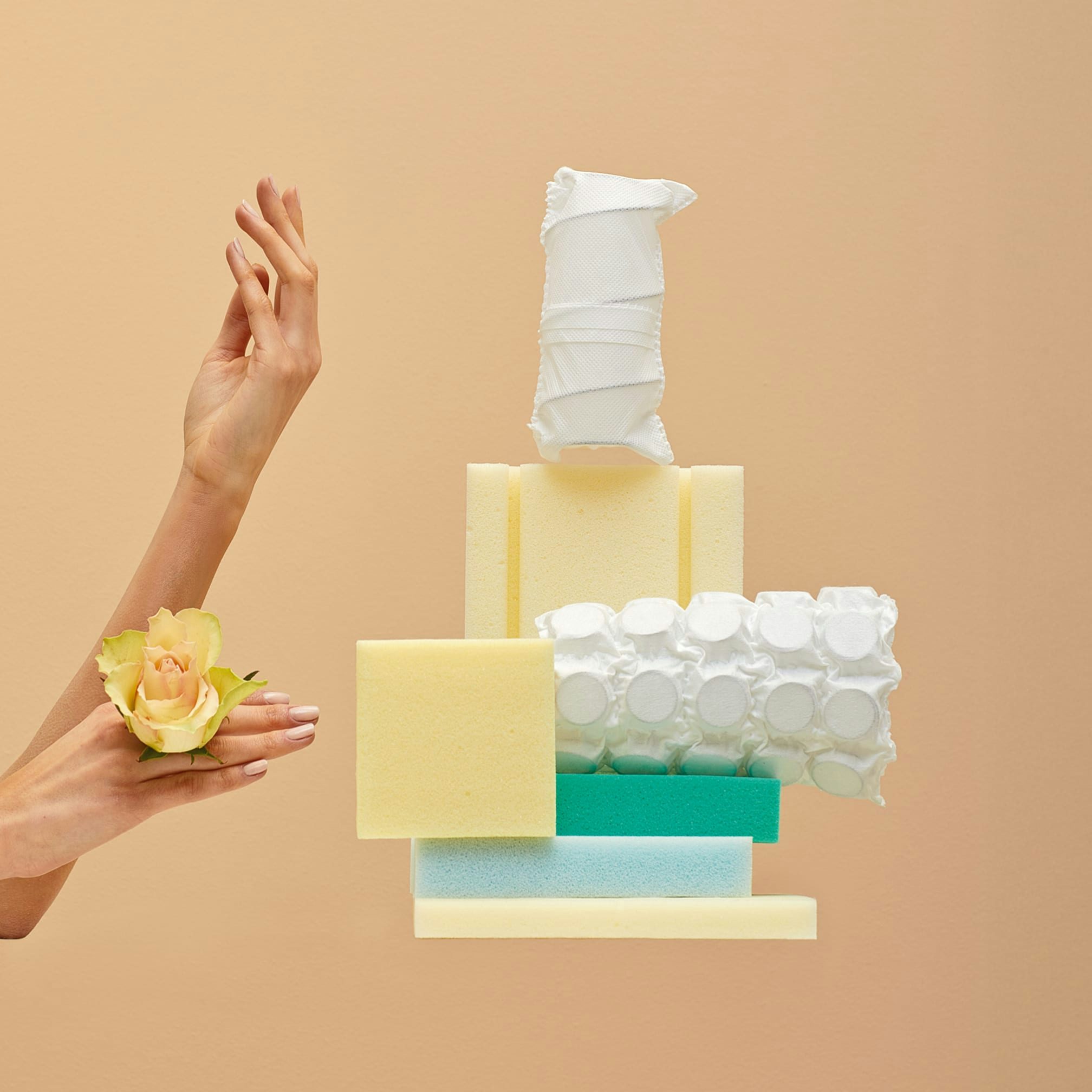 Mani con rosa gialla accanto a diverse tipologie di spugne e assorbenti femminili su sfondo beige.