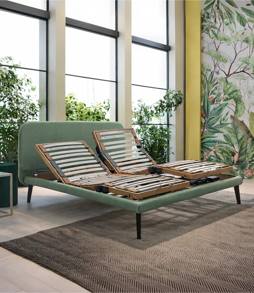 Letto matrimoniale con rete regolabile in legno, struttura verde e testiera imbottita in ambiente con grandi finestre e…