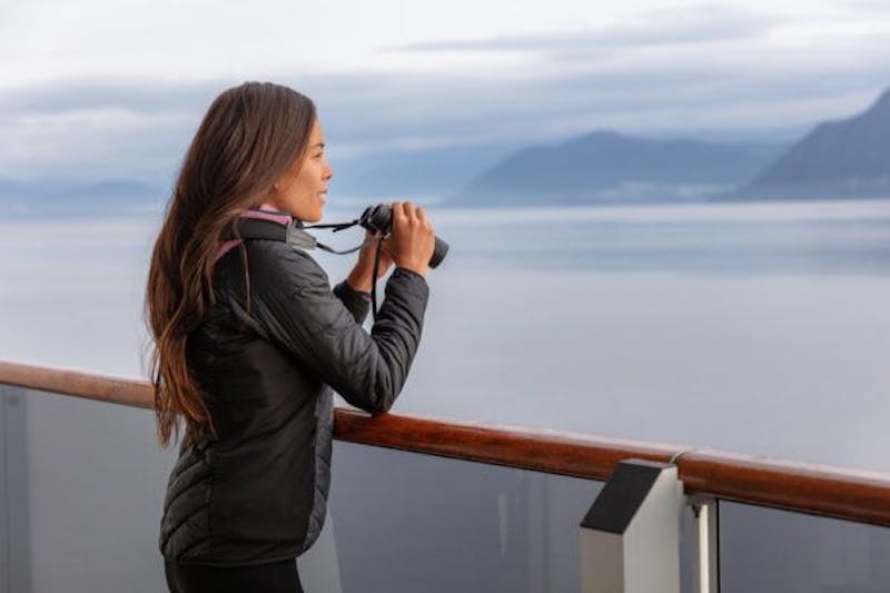 woman looking at mountains out of binoculars