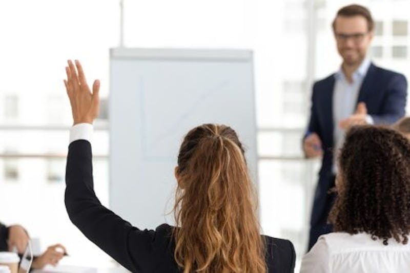 Business woman raising her hand in a conference