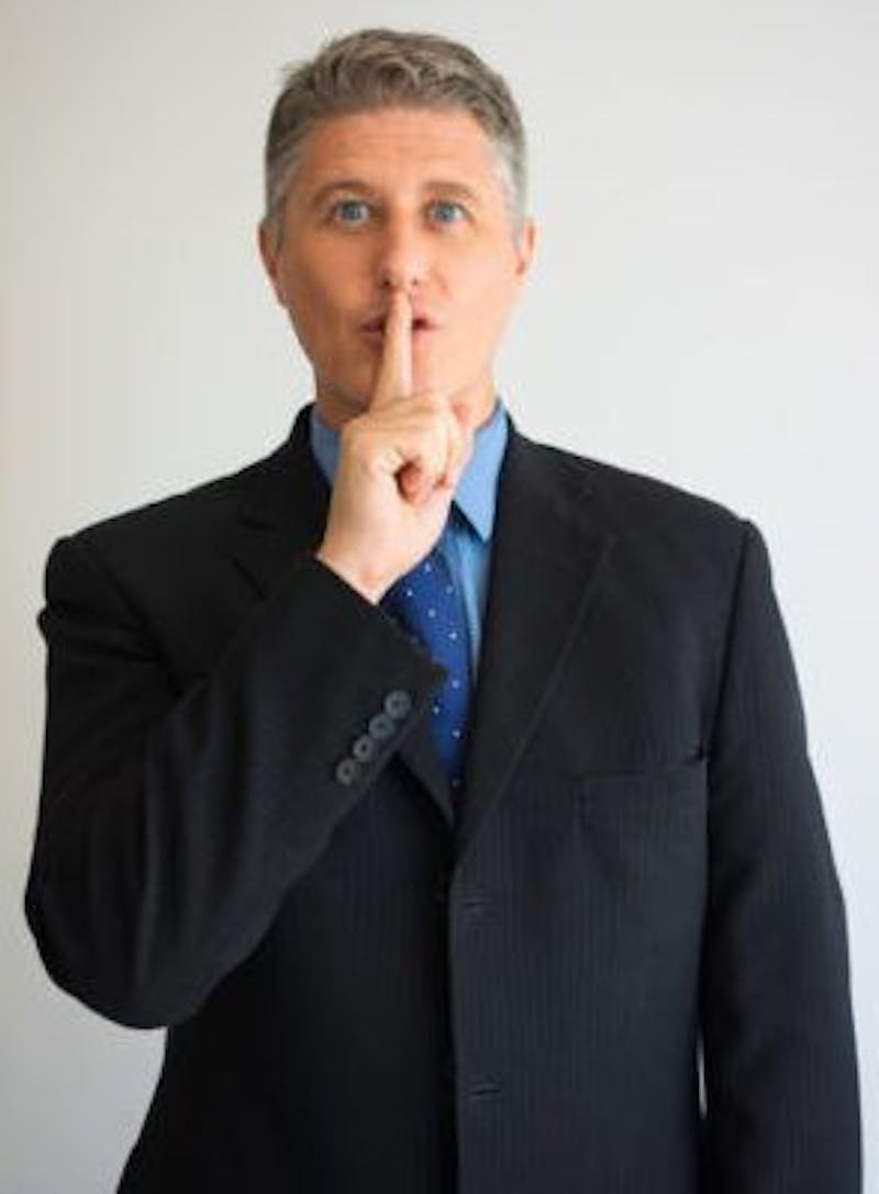 Man in a suit with his finger over his mouth