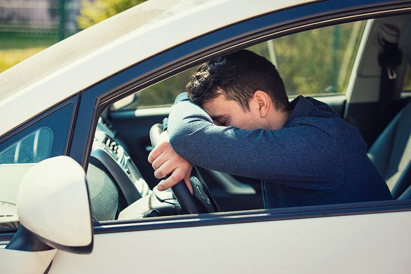 Man sitting with his head against his steering wheel