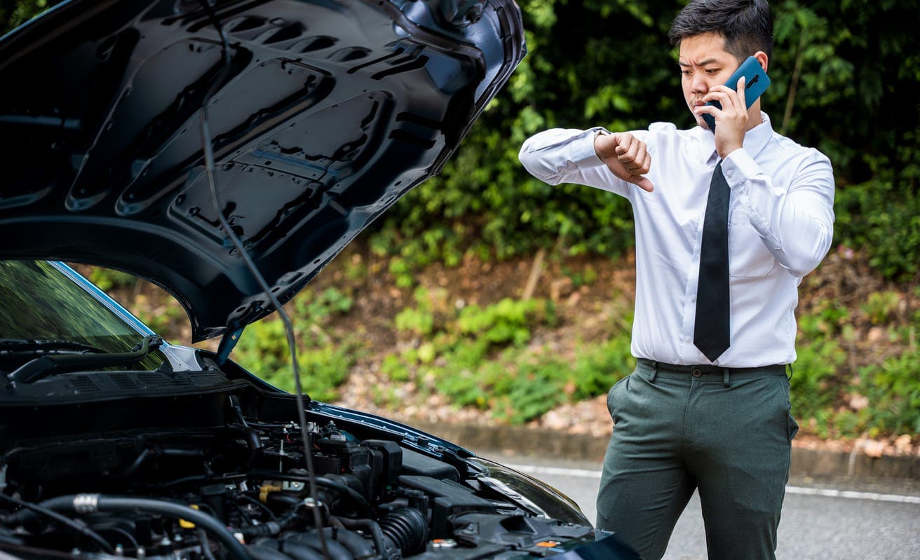 Man on his phone in front of a car