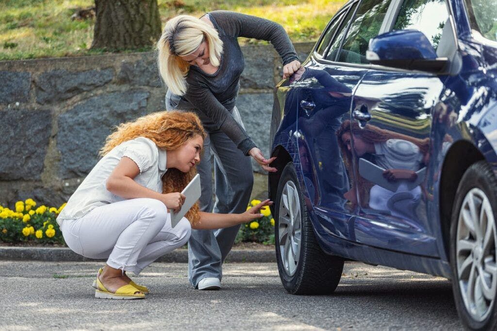 Two women looking at a car tire