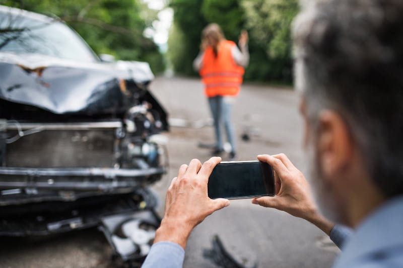 man taking a photo of wrecked vehicle