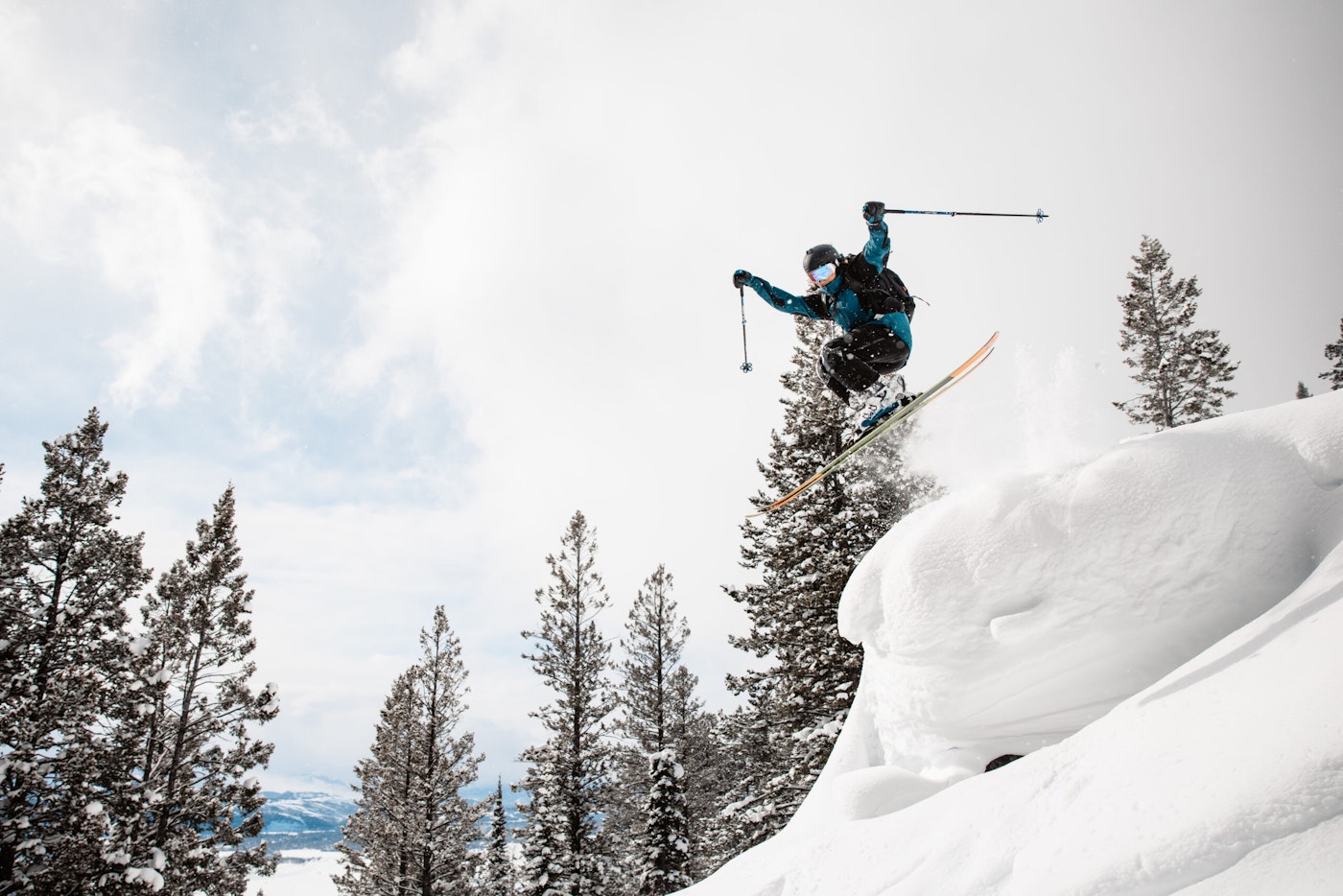 Skier jumping off snowy cliff into deep snow