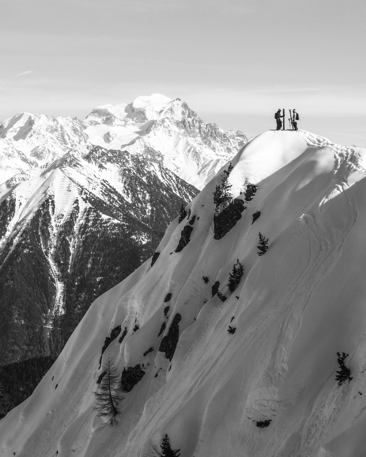 Skiers Laurent De Martin & Sampo Vallotton on top of a snowy peak in a mountain range