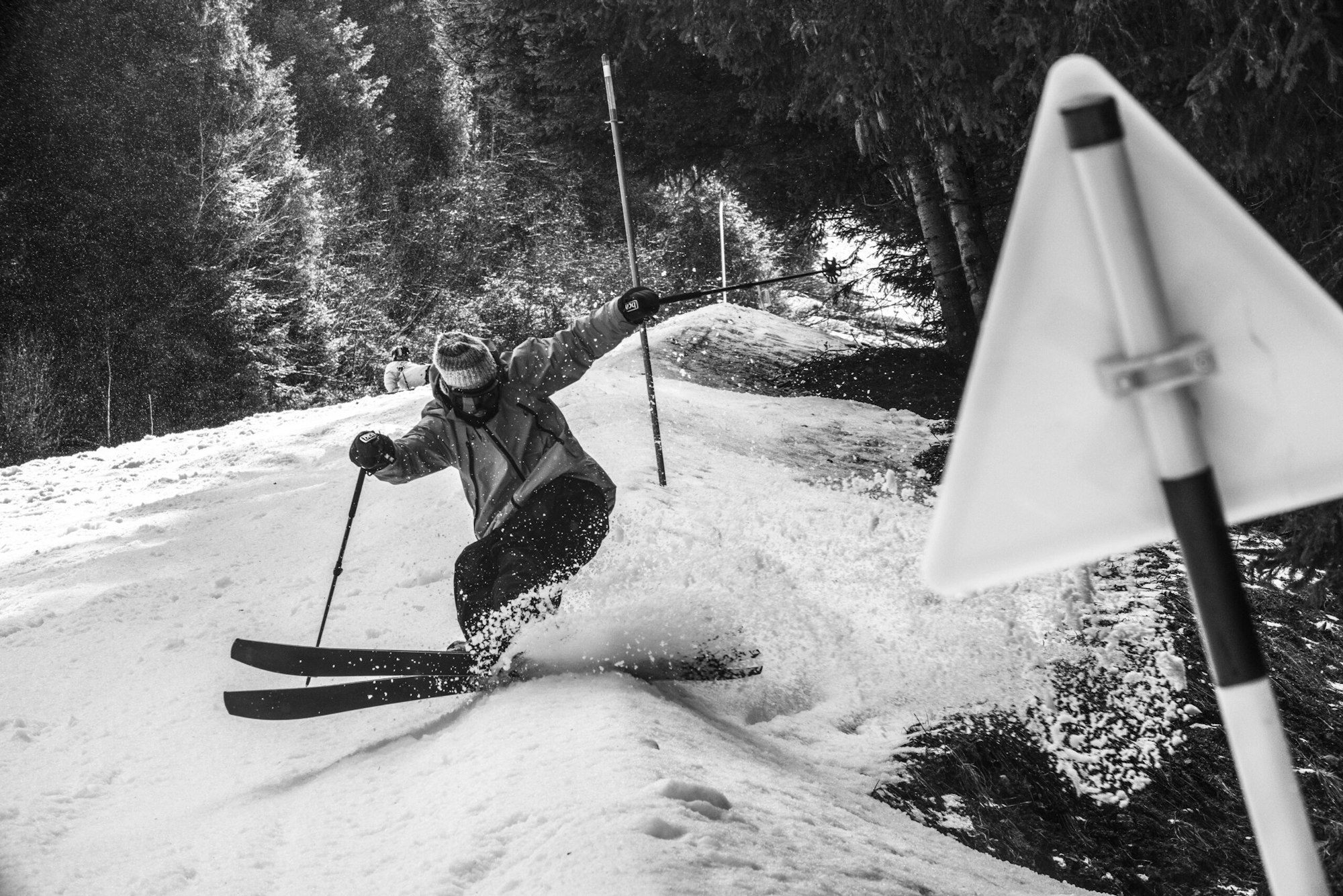 Skier stopping suddenly on a snowy slope in front of a street sign