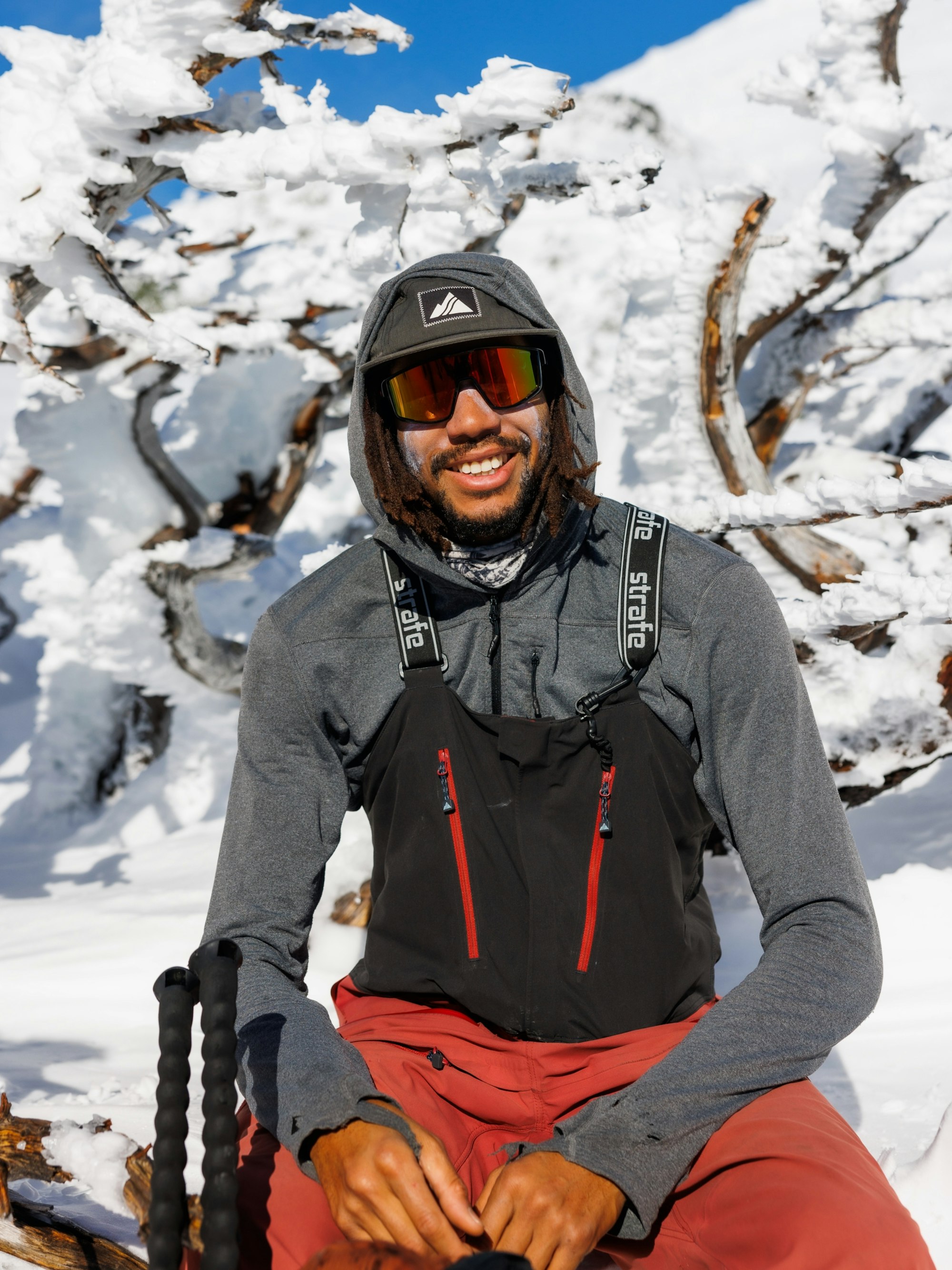 Mallory Duncan sits in the snow smiling wearing ski clothes