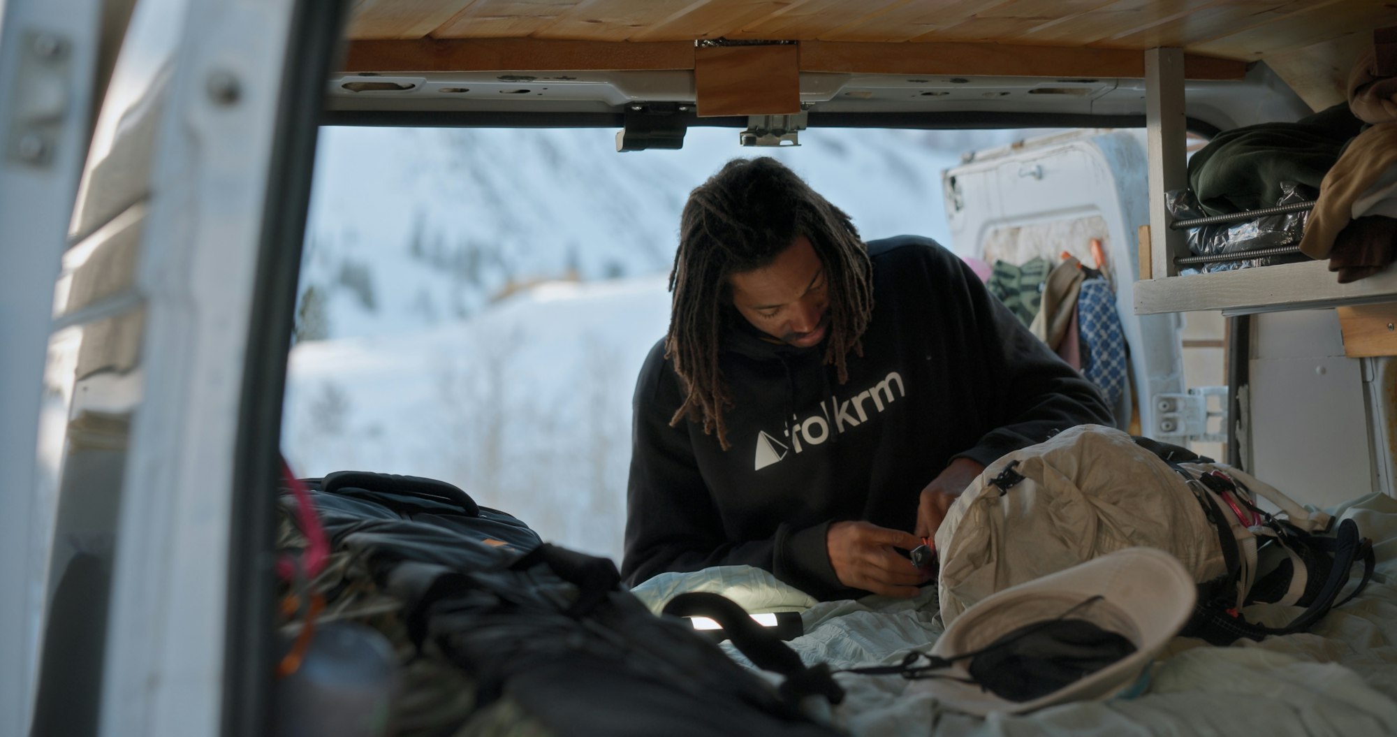 Mallory Duncan in the back of a camper van opening his backpack