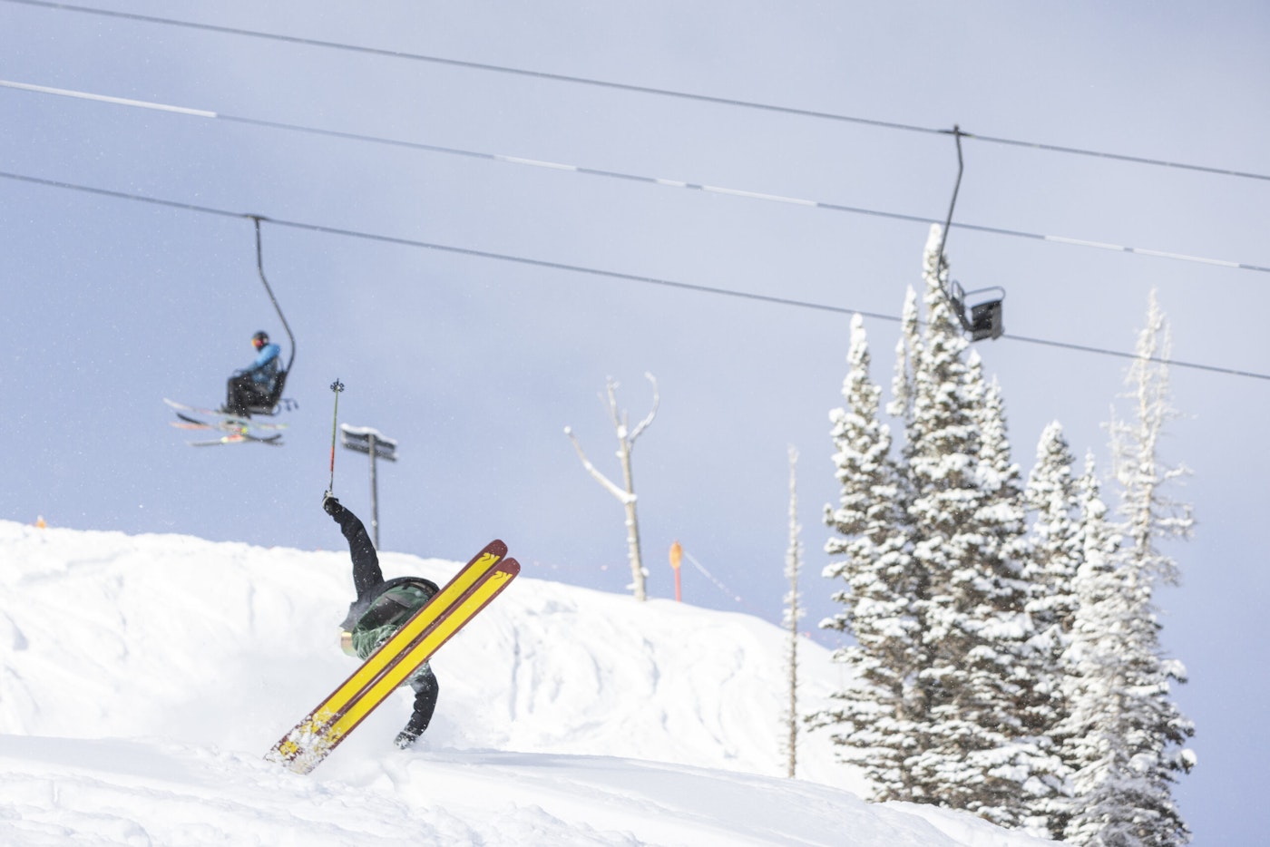Skier Karl Fostvedt spins on skis below a lift where onlookers gape