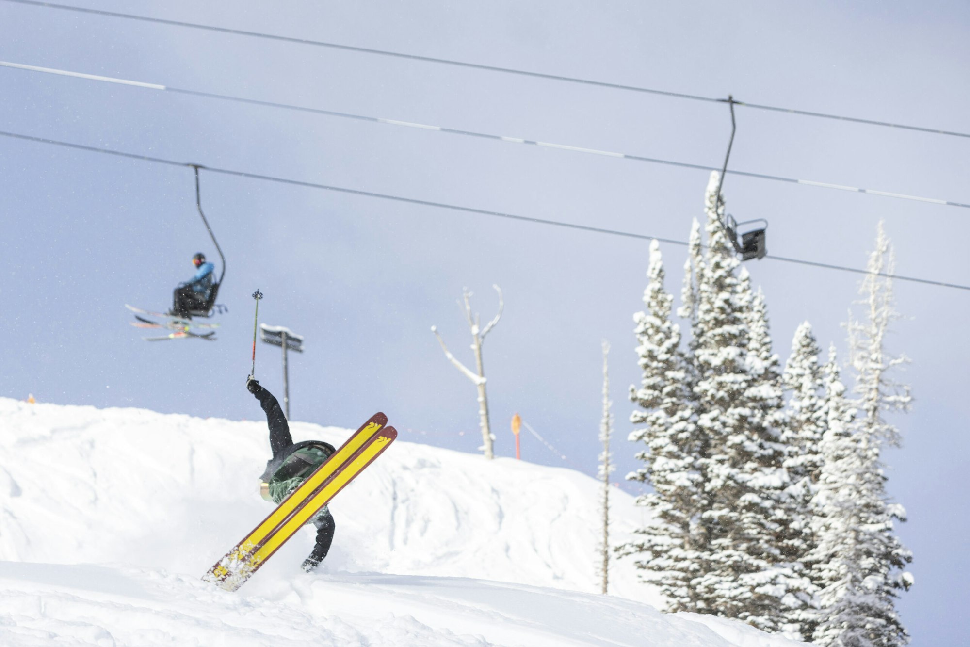 Skier Karl Fostvedt spins on skis below a lift where onlookers gape