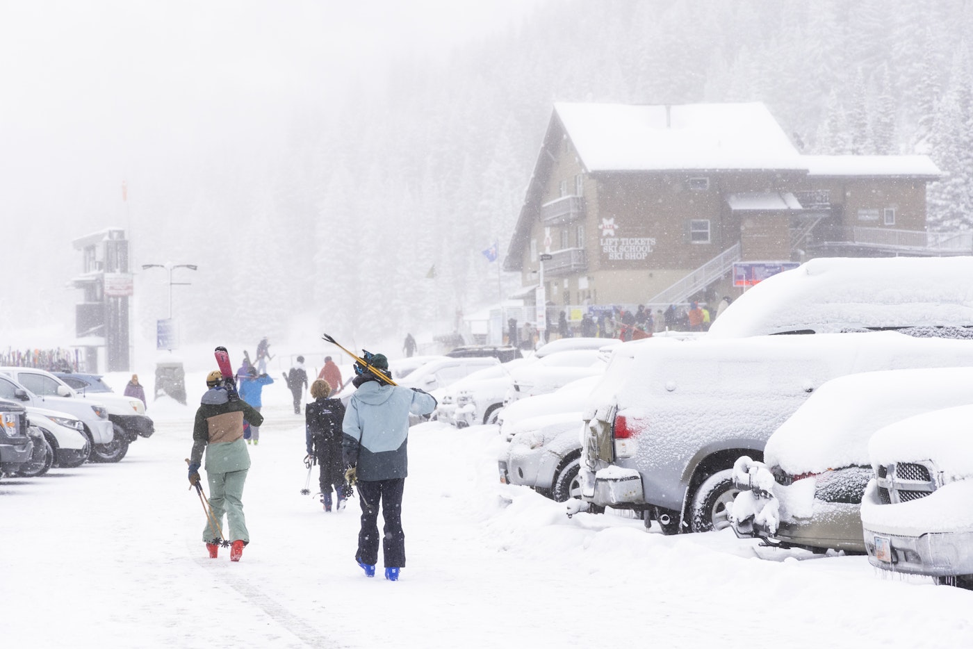 Skiers walk through snowy Alta parking lot to the base lift
