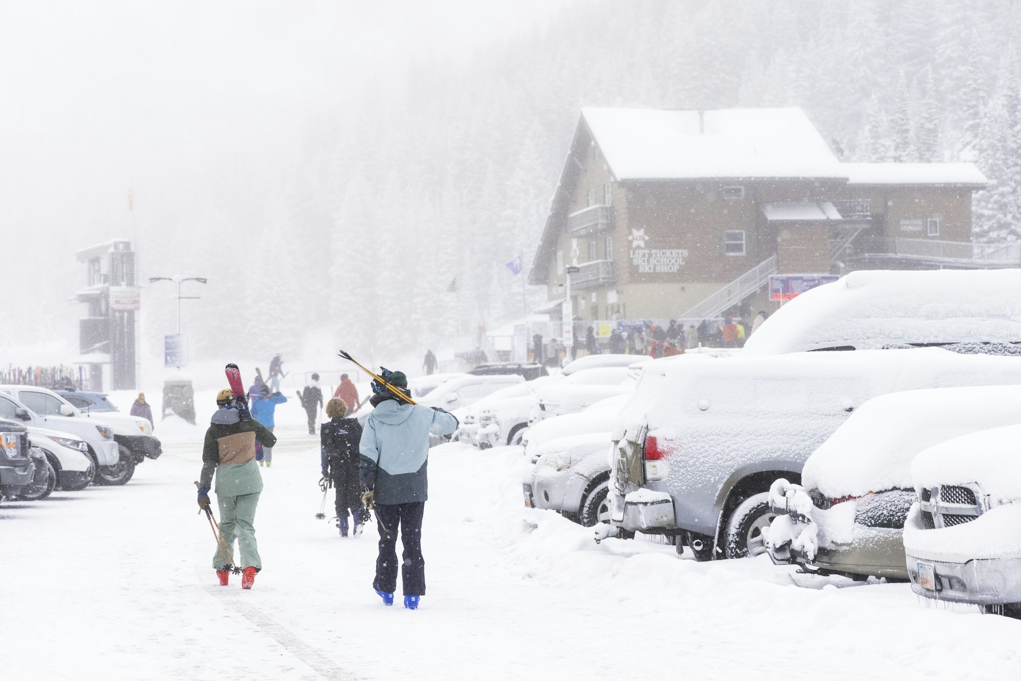Skiers walk through snowy Alta parking lot to the base lift