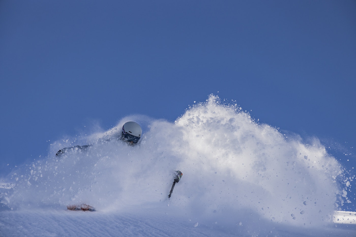 Skier Taylor Pratt skiing through deep snow on a blue sky day