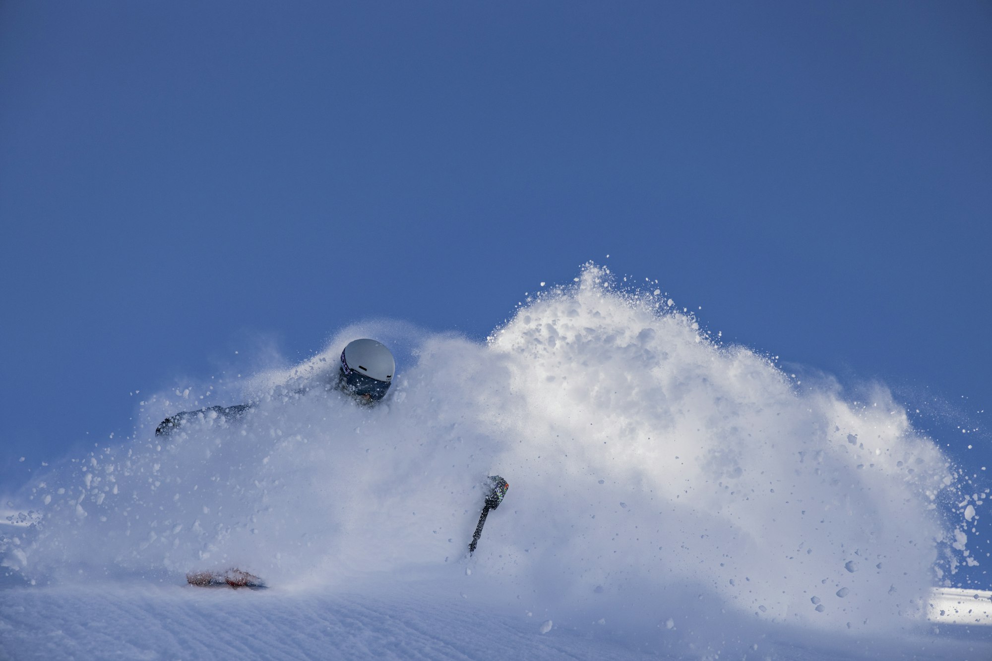 Skier Taylor Pratt skiing through deep snow on a blue sky day