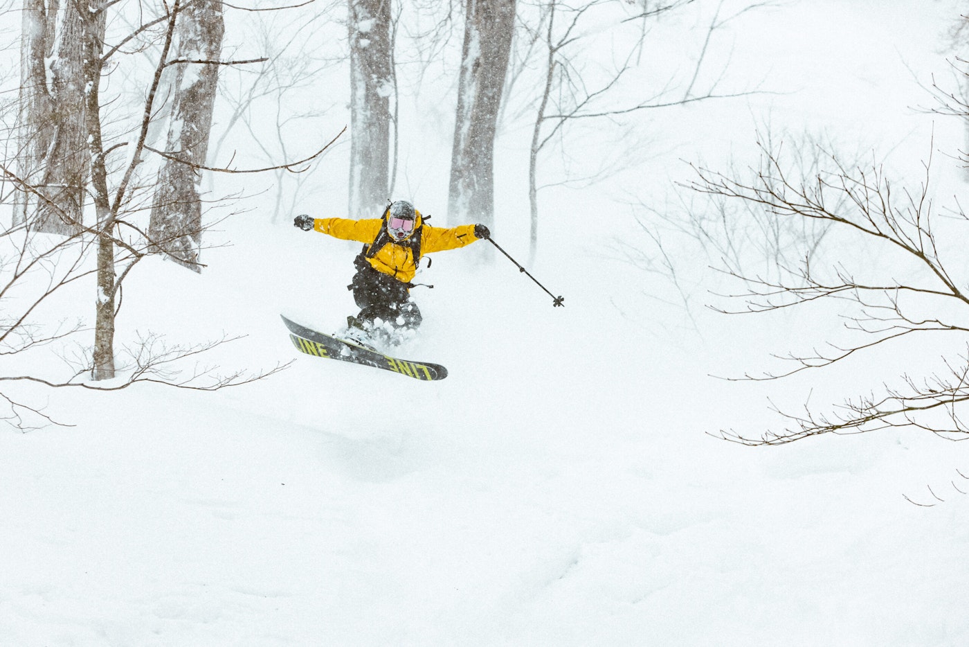 Skier Taylor Brooke Lindquist jumping through deep snow in the trees