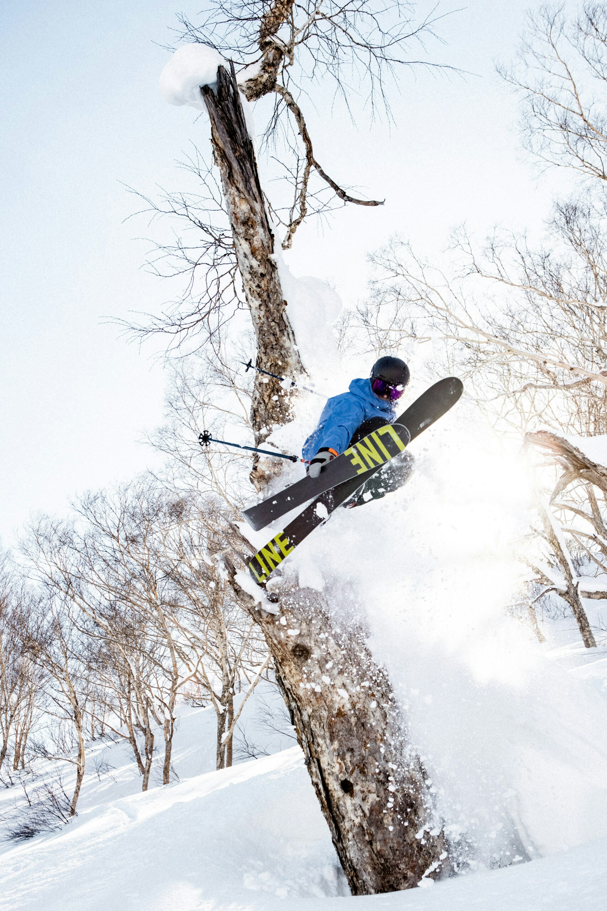 Skier Robert Ruud grabbing skis in the air in deep snow in the forest
